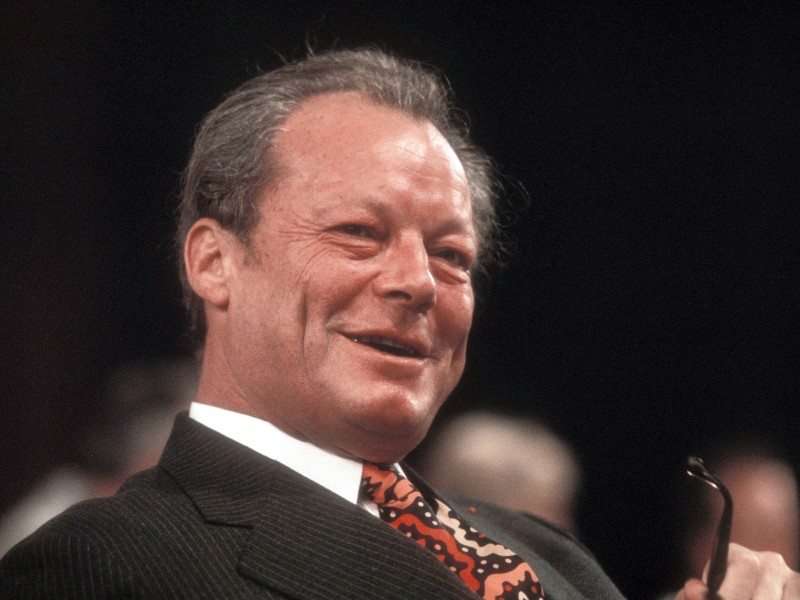 Willy Brandt (*18. Dezember 1913, † 8. Oktober 1992) war der erste Bundeskanzler aus den Reihen der SPD, deren Vorsitzender er von 1964 bis 1987 war. Im Kabinett Kiesinger war er zuvor als Außenminister und Vizekanzler tätig, bis 1957 war er Regierender Bürgermeister von Berlin gewesen. In seiner Zeit als Kanzler von 1969 bis 1974 sorgte Brandt vor allem für eine Annäherung an die Staaten des damaligen Ostblocks – eine erste Entspannung in Zeiten des Kalten Kriegs. Weltberühmt wurde sein „Kniefall von Warschau“ im Dezember 1970, mit dem er in der polnischen Hauptstadt um Vergebung für die NS-Verbrechen bat. Für seine Entspannungspolitik erhielt der Brandt 1971 den Friedensnobelpreis. Wegen der Affäre um den Kanzleramtsspion Günter Guillaume trat er im Mai 1974 zurück.