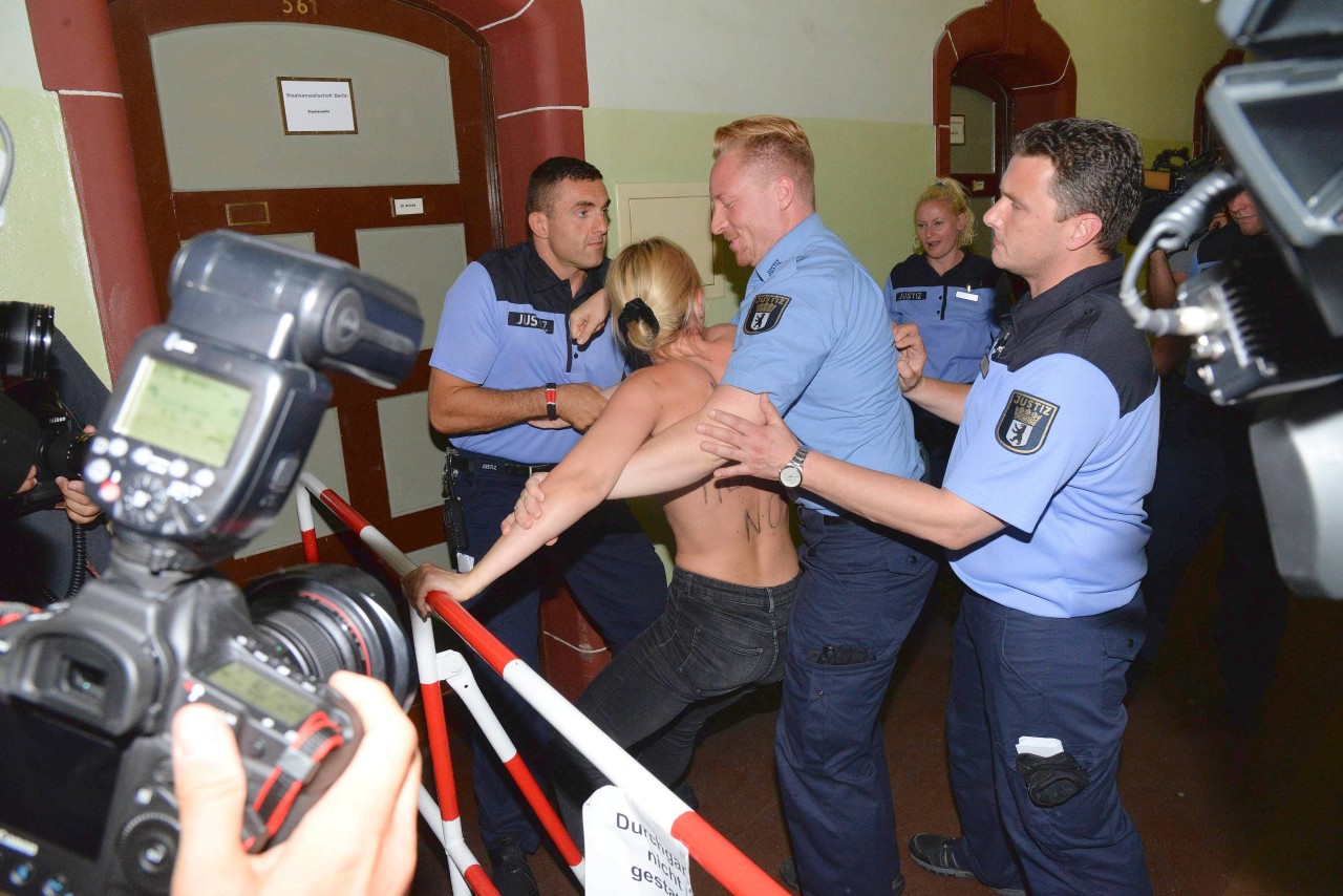Polizisten mussten eine Femen-Aktivistin, die mit nacktem Oberkörper vor dem Verhandlungssaal demonstrierte, aus dem Gerichtsgebäude führen.