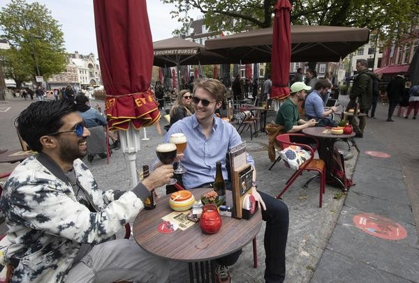 Männer stoßen auf einer Café-Terrasse in Utrecht an. Die Niederlande haben einige Einschränkungen zur Eindämmung der Corona-Pandemie gelockert und unter anderem Bereiche der Außengastronomie wieder geöffnet. 