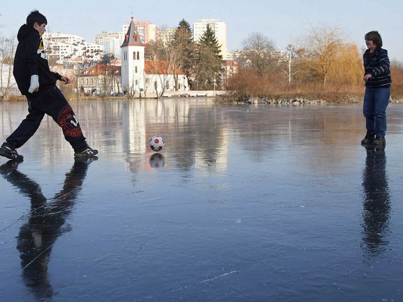 ...ist es in Osteuropa. In Prag spielen  Jungen Fußball auf einem zugefrorenen Teich,...