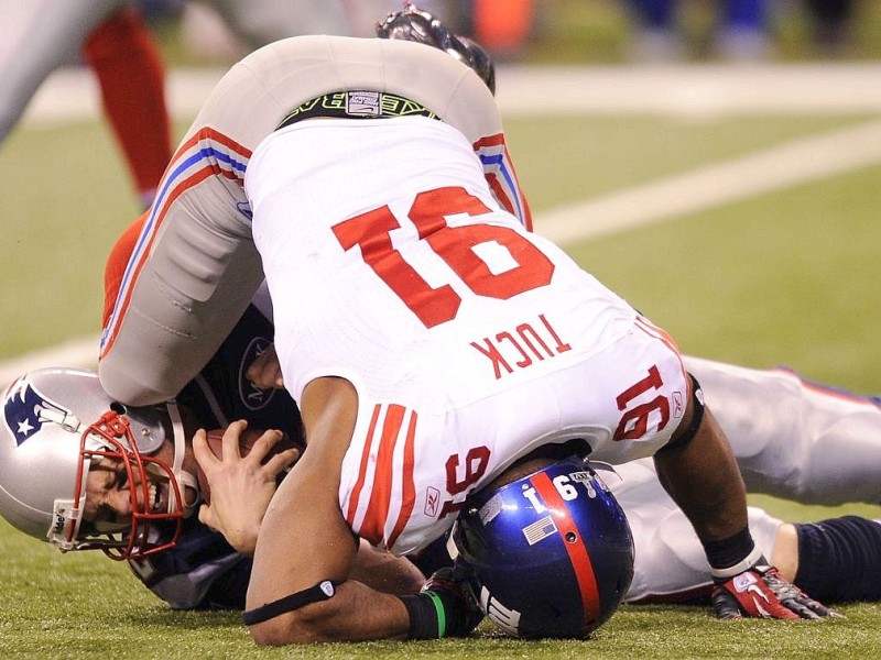 Quarterback Tom Brady (L) of the New England Patriots is sacked by Justin Tuck (R) of the New York Giants during Super Bowl XLVI on February 5, 2012 at Lucas Oil Stadium in Indianapolis, Indiana. The Giants defeated the Patriots 21-17. AFP PHOTO / TIMOTHY A. CLARY
