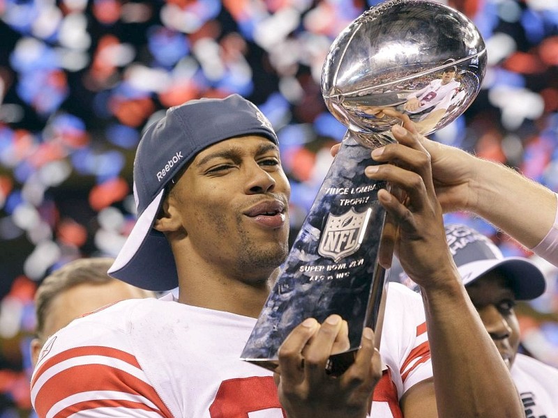 New York Giants wide receiver Victor Cruz holds up the Vince Lombardi Trophy while celebrating his team's 21-17 win over the New England Patriots in the NFL Super Bowl XLVI football game, Sunday, Feb. 5, 2012, in Indianapolis.  (AP Photo/David J. Phillip)