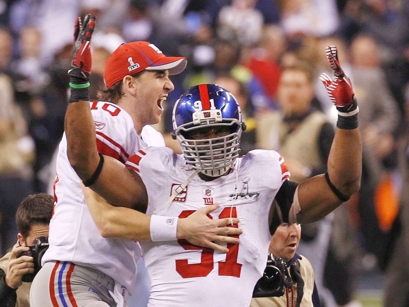 New York Giants quarterback Eli Manning jumps onto defensive end Justin Tuck after defeating the New England Patriots in the NFL Super Bowl XLVI football game in Indianapolis, Indiana, February 5, 2012. REUTERS/Jim Young (UNITED STATES  - Tags: SPORT FOOTBALL TPX IMAGES OF THE DAY)