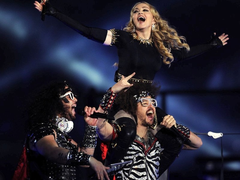 Singer Madonna (R) performs with Redfoo and Sky Blu (L) of LMFAO during the NFL Super Bowl XLVI game halftime show on February 5, 2012 at Lucas Oil Stadium in Indianapolis, Indiana. AFP PHOTO / TIMOTHY A. CLARY The Giants defeated the Patriots 21-17. AFP PHOTO / TIMOTHY A. CLARY