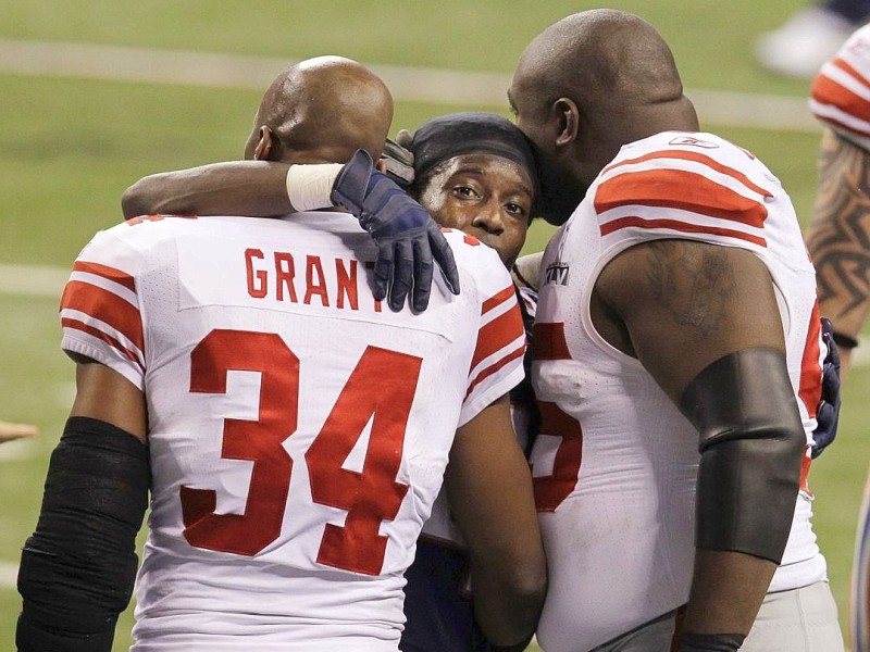 New England Patriots wide receiver Deion Branch, center, hugs New York Giants safety Deon Grant, left, and Rocky Bernard, right, after the NFL Super Bowl XLVI football game, Sunday, Feb. 5, 2012, in Indianapolis. The Giants won 21-17. (AP Photo/Elise Amendola)