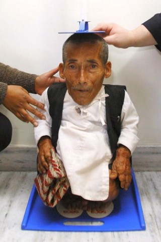 Chandra Bahadur Dangi, 72, who claims to be the world's shortest man standing at a height of 22 inches (56 centimeters), is measured by the Editor-in-Chief of Guinness World Record Craig Glenday (R) and Dr. Rashila Pradhan (L) in Kathmandu February 26, 2012. Dangi will beat Junrey Balawing of Philippines, the current Guinness World who stands at a height of 23.5 inches (60 cm), if he is certified to be shorter then Junrey.   REUTERS/Navesh Chitrakar (NEPAL - Tags: SOCIETY TPX IMAGES OF THE DAY)