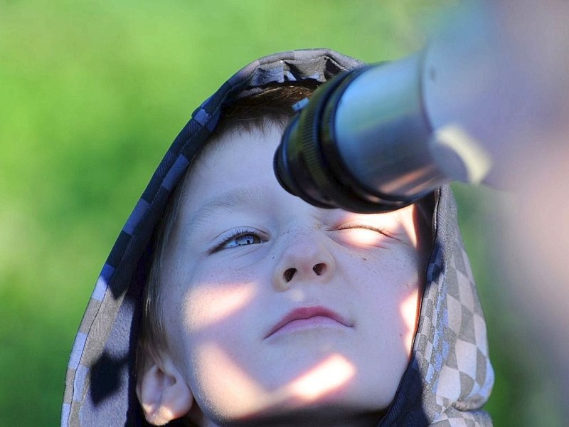 Der Junge sieht durch ein Teleskop in den Himmel, um das Naturphänomen zu beobachten.
