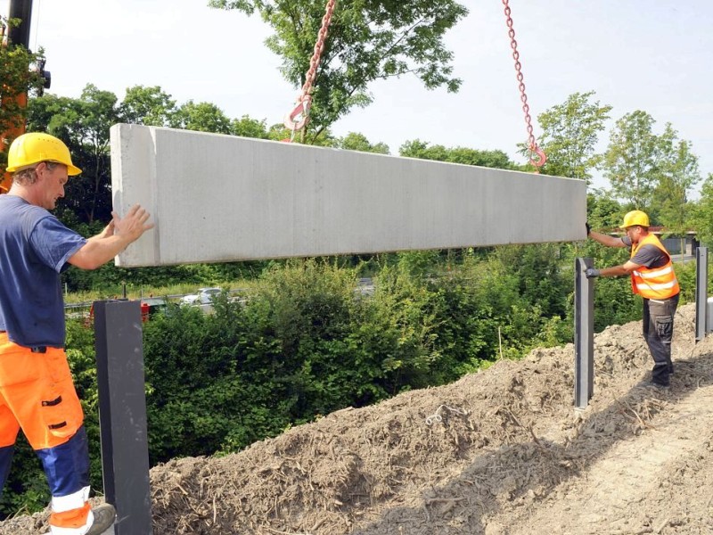 Aufstellen von Lärmschutzwänden an der A 42 am Mittwoch, 04.07.2012 Castrop - Rauxel, Heiko Rietz 8re.) bugsiert den Betonsockel mit seinem Kollegen in die richtige Position. Foto: Karl Gatzmanga / WAZ FotoPool