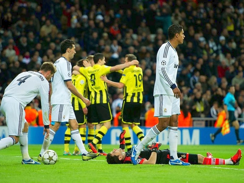 MADRID, SPAIN - NOVEMBER 06: Goalkeeper Iker Casillas (R) of Real Madrid lays defeated on the pitch while Mario Gotze of Borussia Dortmund celebrates with his teammates in the background after scoring his sides second goal during the UEFA Champions League group D match between Real Madrid and Borussia Dortmund at Estadio Santiago Bernabeu on November 6, 2012 in Madrid, Spain.  (Photo by Jasper Juinen/Getty Images)