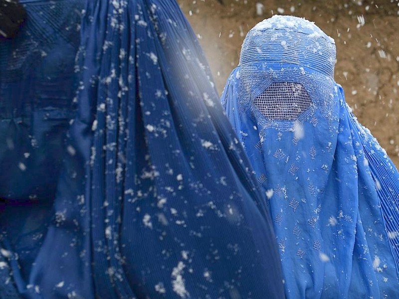 ...wärmt die Burka die Frau in Afghanistan, die auf Winter-Vorräte wartet. Mit...