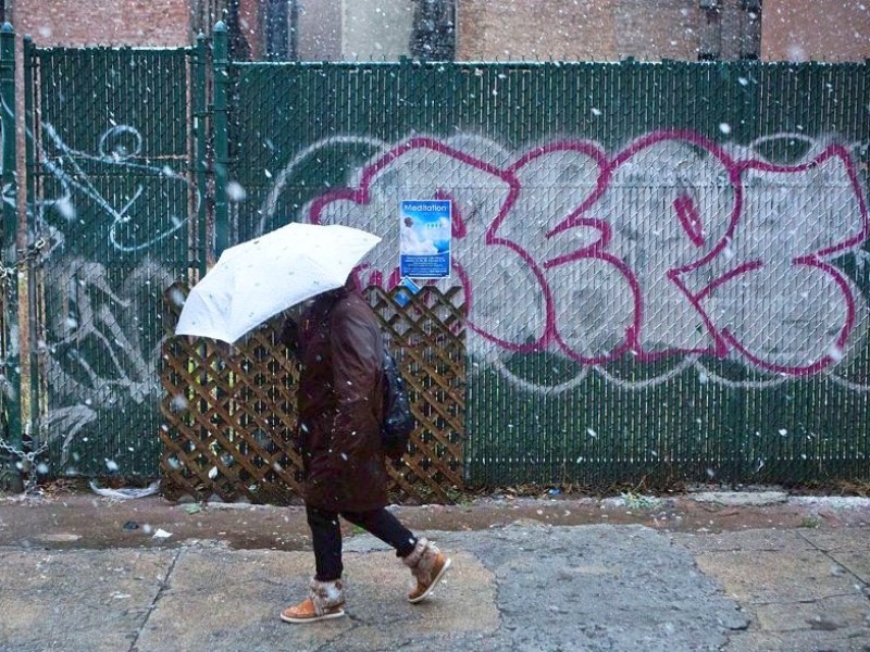 ...einem Schirm schützt sich die New Yorkerin vor dem Schnee: Der Blizzard, der aus dem...