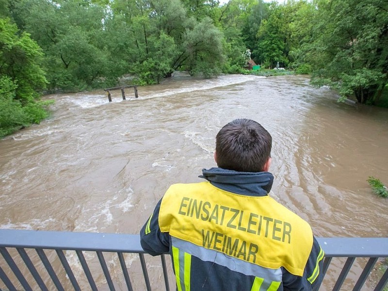 Ein Feuerwehrmann beobachtet das Hochwasser an der über die Ufer getretenen Ilm in Taubach, Thüringen.