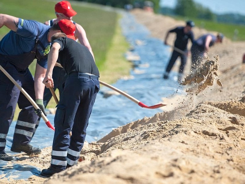 Helfer bauen bei Hitzacker (Niedersachsen) einen zusätzlichen Damm aus Sand und Folie auf dem Elbdeich.