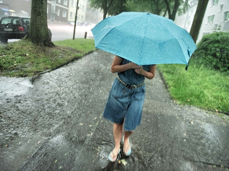 Starke Regenfälle überschwemmen die Straßen in Bochum-Weitmar, am Donnerstag, den 20. Juni  2013 in Bochum. Eine Frau geht in Sommergarderobe mit einem Schirm über den überfluteten Bürgersteig.  Foto: Ingo Otto / WAZ FotoPool