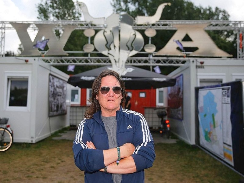 Thomas Jensen, Gründungsmitglied des Wacken-Open-Air-Festivals, posiert vor dem Logo des Festivals.