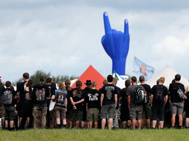 Besucher des Wacken-Open-Air-Festivals warten auf dem Festivalgelände auf den Beginn einer Veranstaltung.
