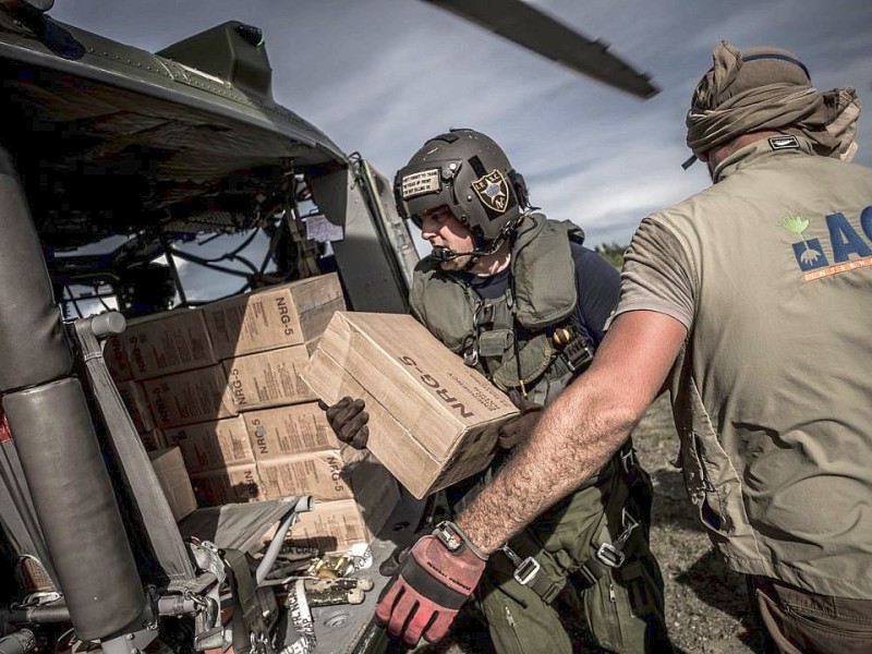 Katastrophenhelfer von ACF, einer Partnerorganisation der Kindernothilfe beladen einen Hubschrauber der Kanadischen Armee mit Nahrungspaketen. Die Notfallnahrung versorgt die Menschen für 14 Tage. Die Kanadische Armee fliegt die Hilfsgüter un unzugängliche Gebiete in den Bergen.  Die Katastrophenhelferin Lucile von ACF führt Angelika Böhling durch die Unglücksgebiete 28.11.2013 auf der Insel Panay - Phillippinen    Bild: Jakob Studnar