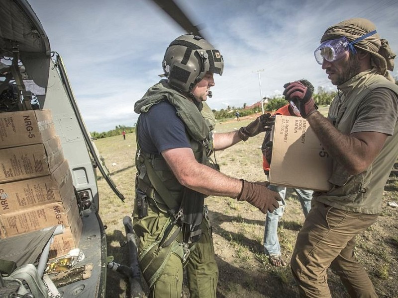 Katastrophenhelfer von ACF, einer Partnerorganisation der Kindernothilfe beladen einen Hubschrauber der Kanadischen Armee mit Nahrungspaketen. Die Notfallnahrung versorgt die Menschen für 14 Tage. Die Kanadische Armee fliegt die Hilfsgüter un unzugängliche Gebiete in den Bergen.  Die Katastrophenhelferin Lucile von ACF führt Angelika Böhling durch die Unglücksgebiete 28.11.2013 auf der Insel Panay - Phillippinen    Bild: Jakob Studnar