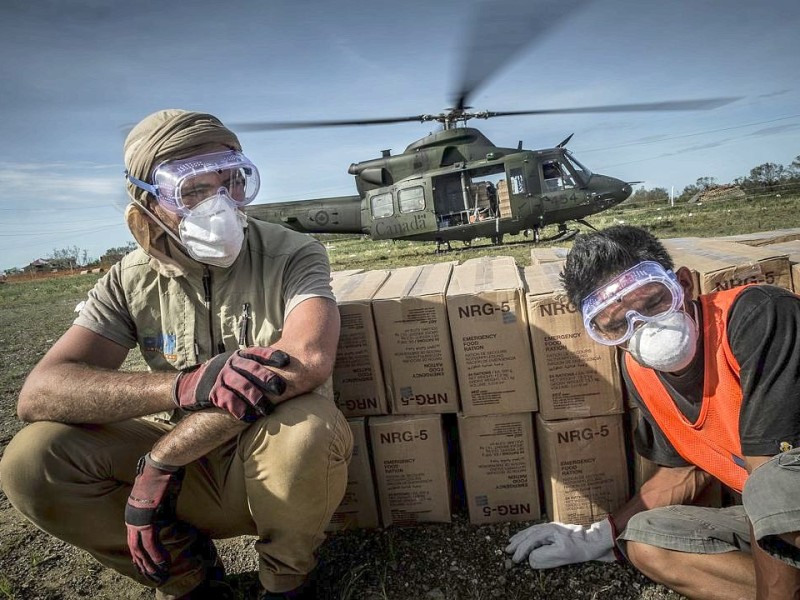 Katastrophenhelfer von ACF, einer Partnerorganisation der Kindernothilfe beladen einen Hubschrauber der Kanadischen Armee mit Nahrungspaketen. Die Notfallnahrung versorgt die Menschen für 14 Tage. Die Kanadische Armee fliegt die Hilfsgüter un unzugängliche Gebiete in den Bergen.  Die Katastrophenhelferin Lucile von ACF führt Angelika Böhling durch die Unglücksgebiete 28.11.2013 auf der Insel Panay - Phillippinen    Bild: Jakob Studnar