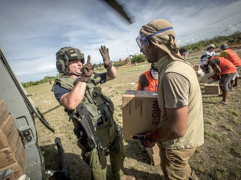 Katastrophenhelfer von ACF, einer Partnerorganisation der Kindernothilfe beladen einen Hubschrauber der Kanadischen Armee mit Nahrungspaketen. Die Notfallnahrung versorgt die Menschen für 14 Tage. Die Kanadische Armee fliegt die Hilfsgüter un unzugängliche Gebiete in den Bergen.  Die Katastrophenhelferin Lucile von ACF führt Angelika Böhling durch die Unglücksgebiete 28.11.2013 auf der Insel Panay - Phillippinen    Bild: Jakob Studnar