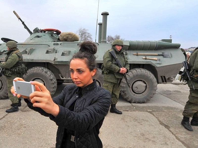 Eine Frau fotografiert bewaffnete Soldaten in der ukrainischen Hafenstadt Feodosiya.