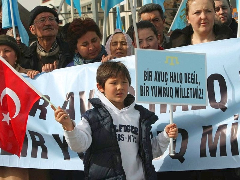 Türken, die ihre Wurzeln auf der Krim haben, protestieren mit Bannern. Ein Junge hält ein Schild, auf dem steht Wir sind keine Handvoll Menschen, sondern eine vereinte Nation!.