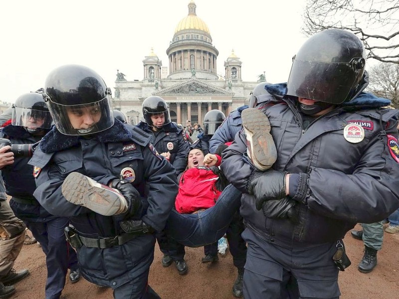In St. Petersburg tragen Polizisten einen Demonstranten fort.