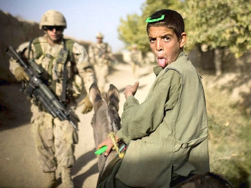 Ein Junge streckt kanadischen Soldaten auf Patrouille die Zunge heraus.