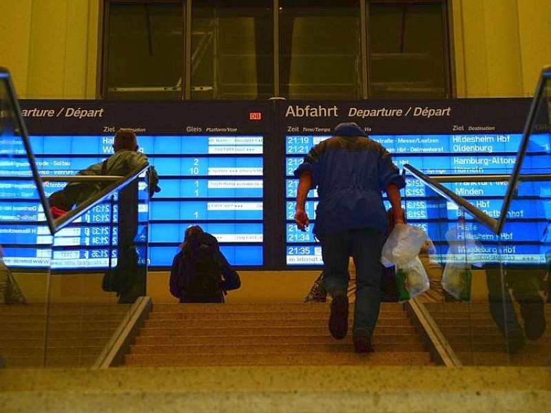 Reisende stehen im Hauptbahnhof in Hannover (vor einem Display.