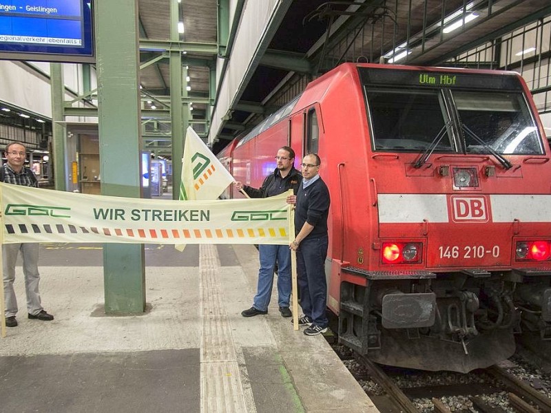 Lokführer mit Fahnen der Gewerkschaft GdL stehen in Stuttgart am Bahnsteig.
