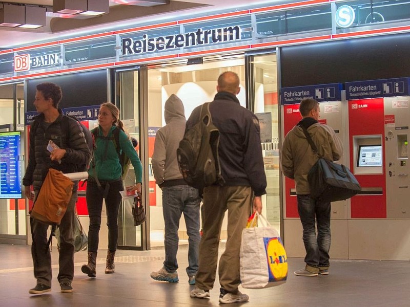 Reisende stehen in Berlin im Hauptbahnhof vor dem Reisezentrum.