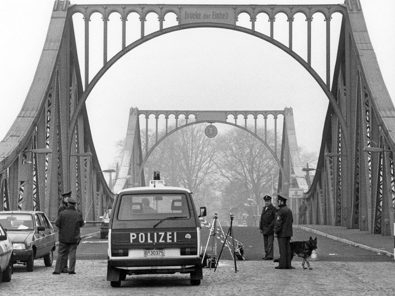 Westberliner Polizisten arbeiten 1988 vor den zum Teil beschädigten Grenzanlagen auf dem westlichen Teil der Glienicker Brücke in Berlin. ...