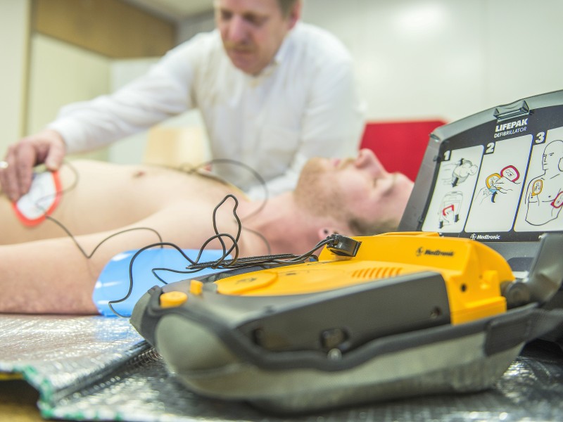 Ist die Bewusstlosigkeit festgestellt, klappt man den Defibrillator (AED) auf, der einen anleitet. Zunächst setzt man den Notruf ab und klebt die Elektroden auf.