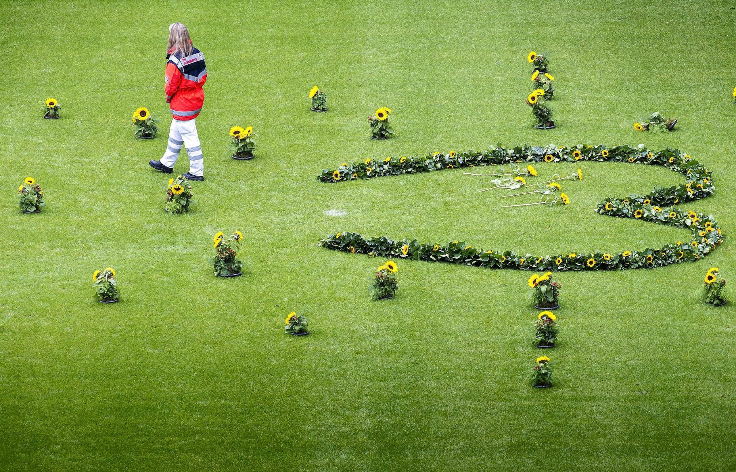 Helfer der Rettungsdienste legten in der MSV-Arena für jedes Todesopfer eine Sonneblume nieder. Bild: Ilja Hoepping / WAZ FotoPool