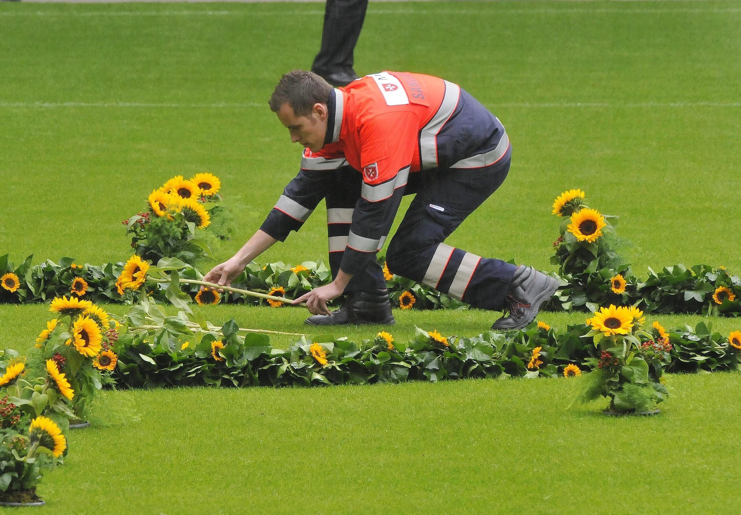 Helfer der Rettungsdienste legten in der MSV-Arena für jedes Todesopfer eine Sonneblume nieder. Foto: Kai Kitschenberg/WAZFotoPool
