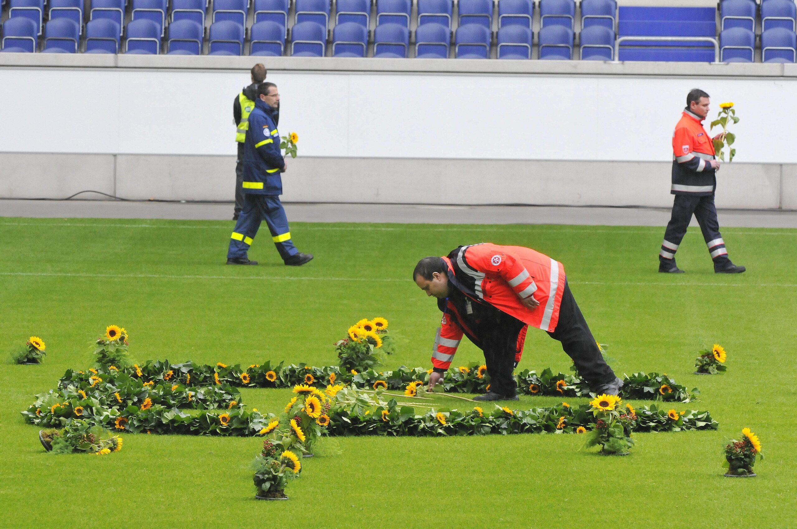 Helfer der Rettungsdienste legten in der MSV-Arena für jedes Todesopfer eine Sonneblume nieder.  Foto: Kai kitschenberg/WAZFotoPool