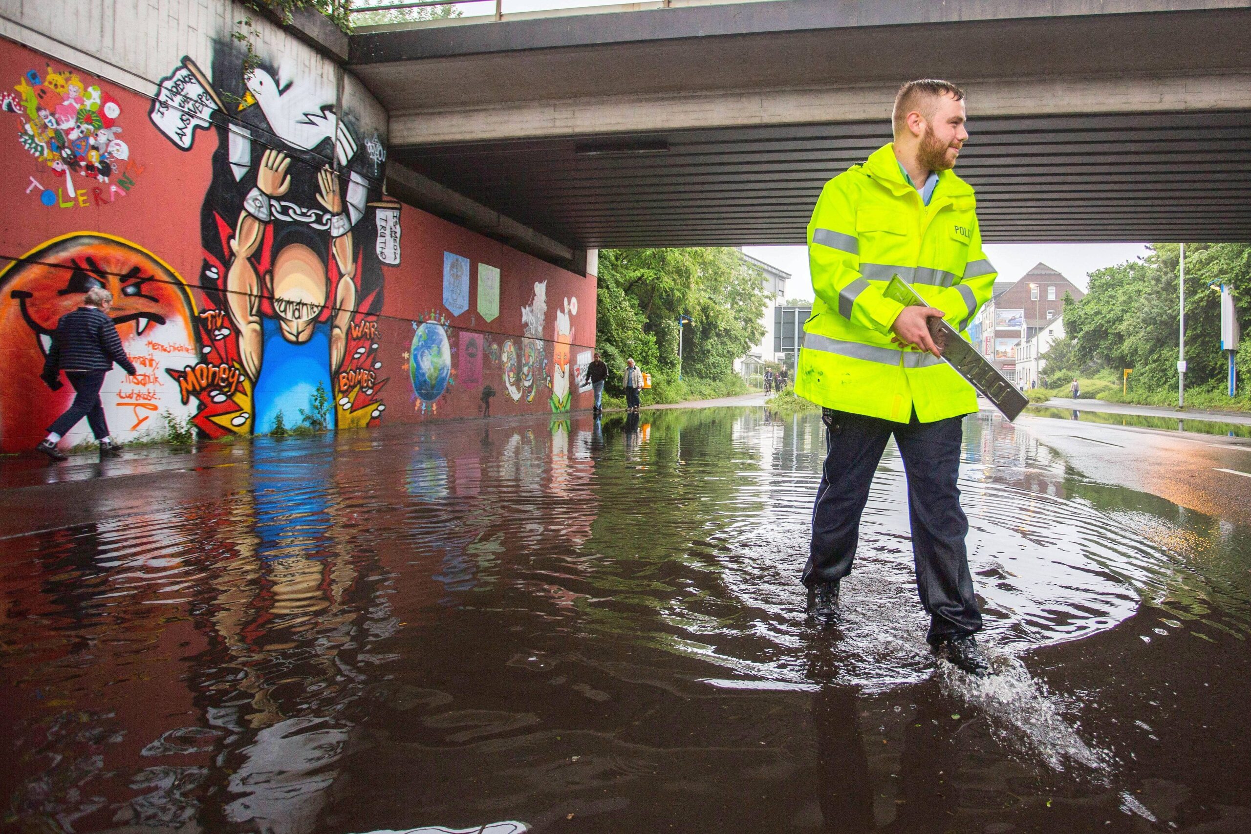 Ein Polizist sucht auf der Hünxer Straße PKW-Kennzeichen in den Wassermassen.