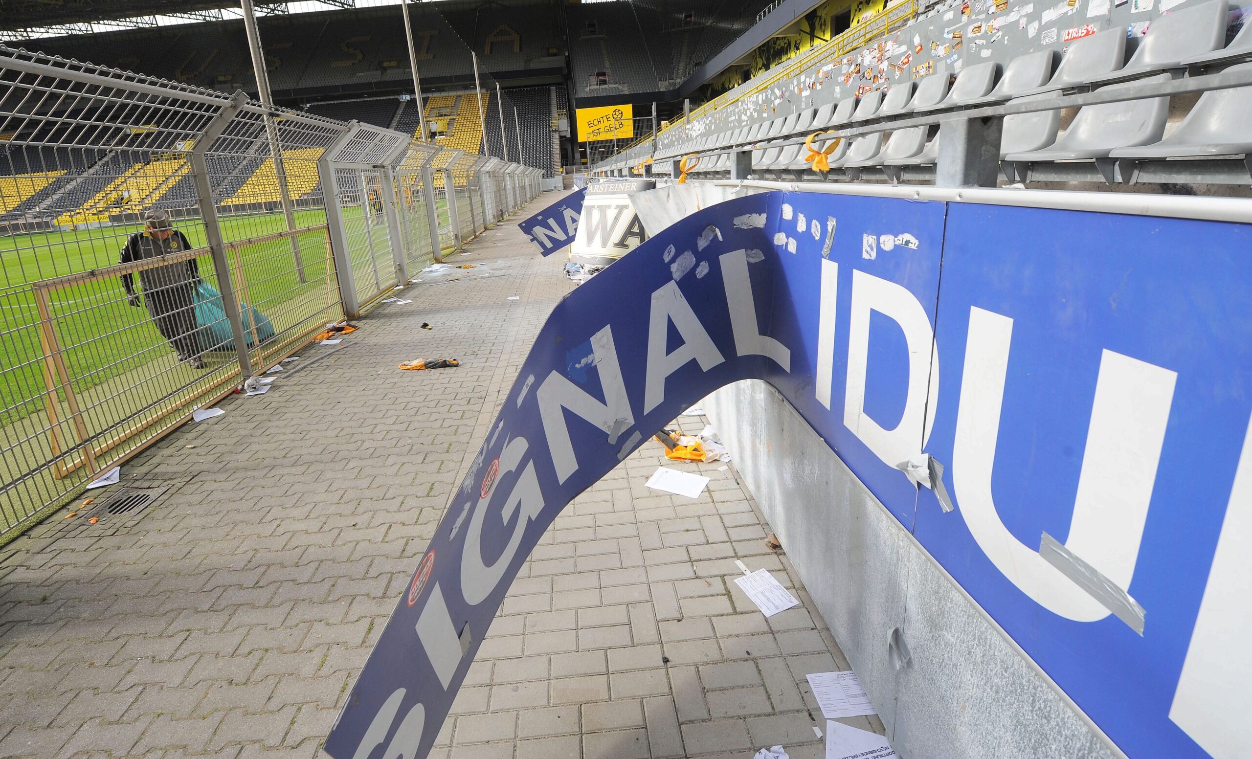 Am Tag nach dem Pokalspiel zwischen Borussia Dortmund und Dynamo Dresden zeigen sich die Schäden am Gästeblock: zerstörte Werbebanden, angekokelte Fahnen und Reste von Pyrotechnik.