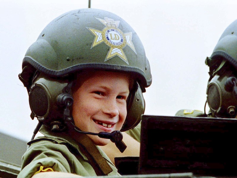 Prinz Harry begeistert sich schon früh für Uniformen und Militär, als Achtjähriger darf er einen Soldaten begleiten und lacht stolz unter seinem großen Helm.