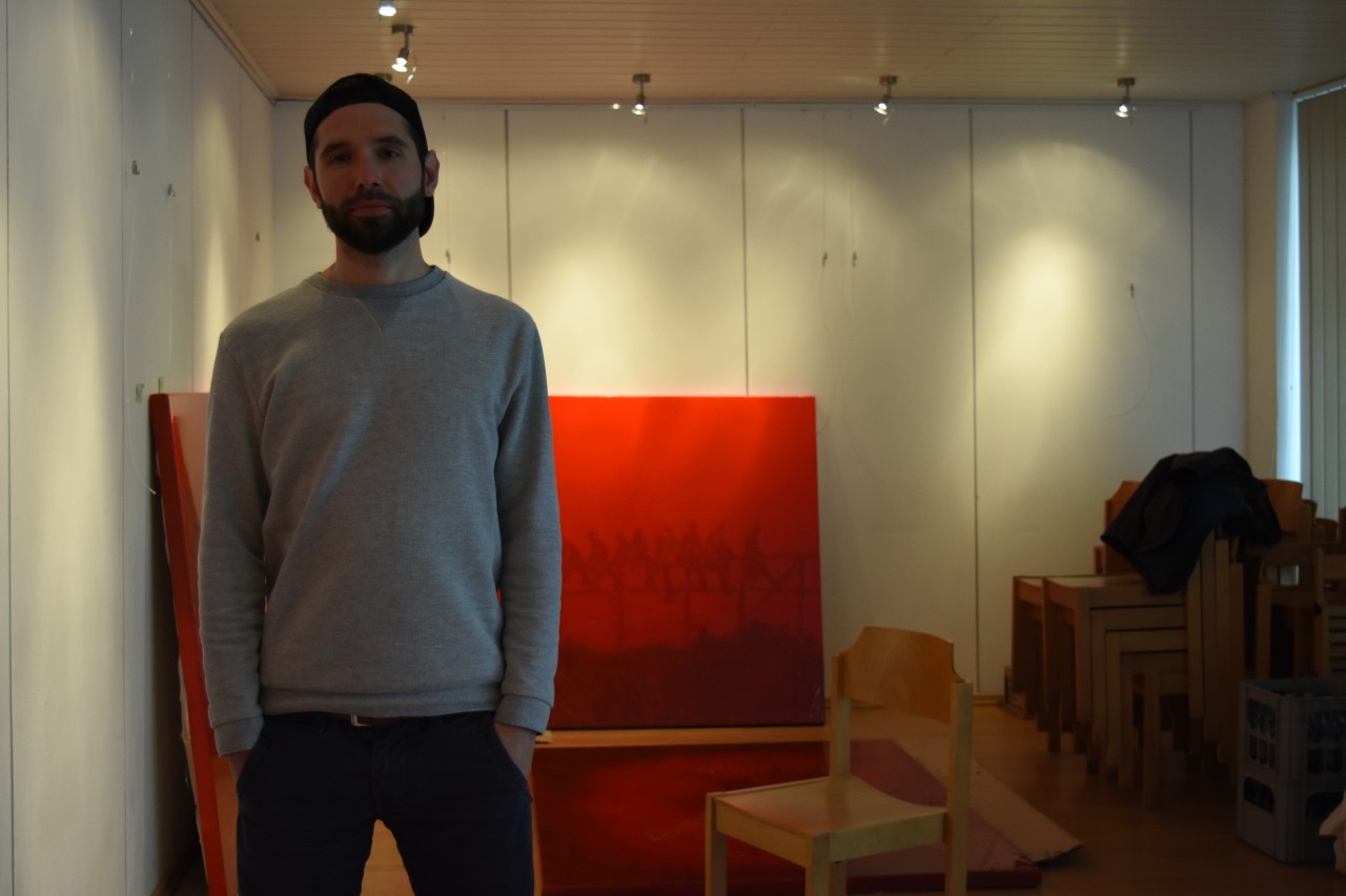 Roman (31) in seinem Atelier Eurasia & pilgrim.art. Im Hintergrund siehst du die Bilder seiner letzten Ausstellung „WAR // ist“.