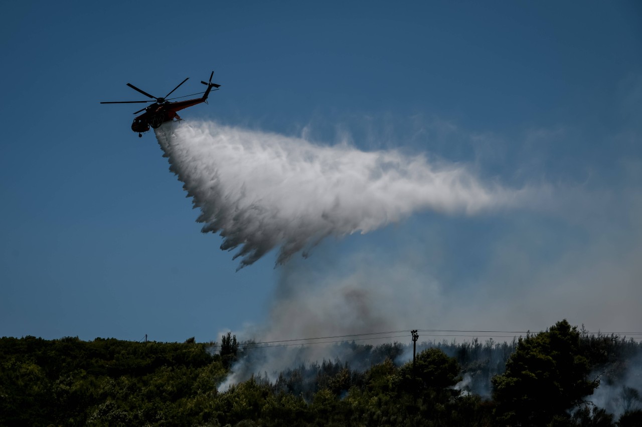 Ein Hubschrauber wirft Wasser über einem Waldbrand ab. 