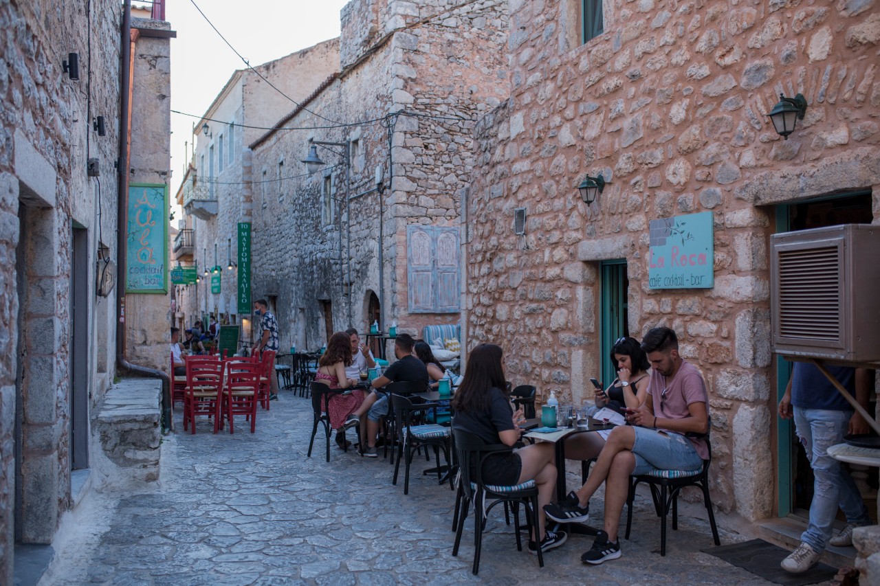 Touristen sitzen in einem Cafe in Areopoli, der Hauptstadt der Halbinsel Mani.