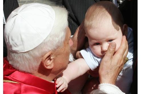 Papst Benedikt XVI. segnet ein Baby.