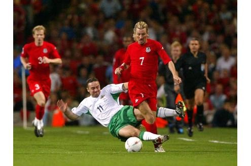 So stellt sich der Festland-Europäer den Fußball auf der Insel doch vor. Michael Hughes (Nordirland) mäht Robbie Savage (Wales) kompromisslos um.