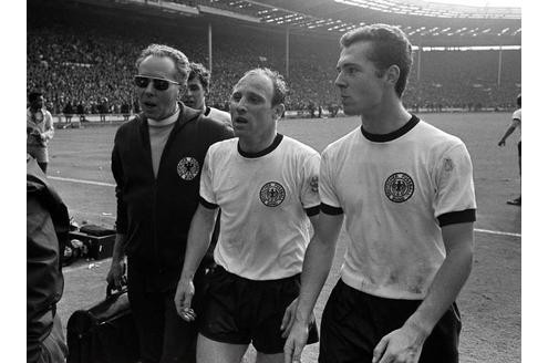 Halbzeit: Masseur Erich Deuser (links) geht mit Uwe Seeler (Mitte) und Franz Beckenbauer in die Kabine. Durch Tore von Helmut Haller und Geoff Hurst steht es 1:1. In Hälfte zwei wird Deutschland abermals in Führung gehen, doch am Ende ...