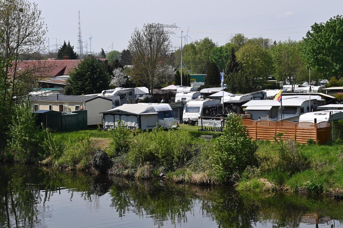 Bewohnte und unbewohnte Campingfahrzeuge stehen auf einem Campingplatz am Havelkanal nebeneinander.