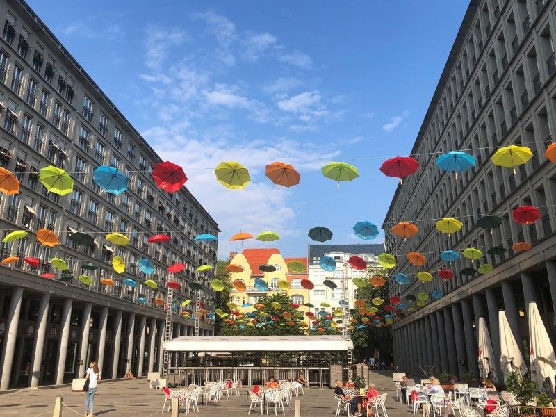 Bunte Regenschirme hängen über dem Walter-Benjamin-Platz im Stadtteil Charlottenburg. Die Reiseführerreihe "52 kleine & große Feierabend-Eskapaden für jedes Wetter" empfiehlt den Ort für einen Kurztrip nach Feierabend.