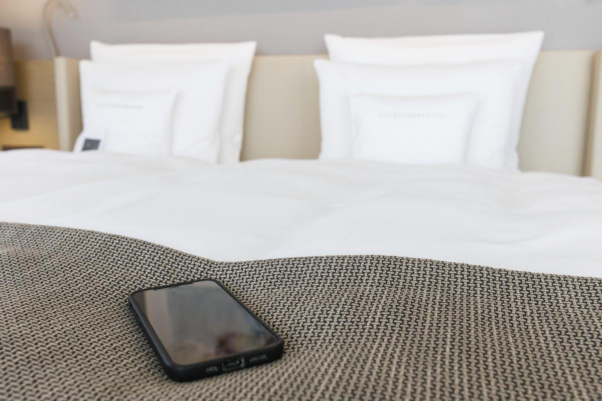 Ein Smartphone liegt am Fußende eines Betts in einem Hotelzimmer des "Öschberghof". (zu dpa: "Volldigital oder Funkloch: Hotels wollen technischen Komfort bieten") Foto: Philipp von Ditfurth/dpa