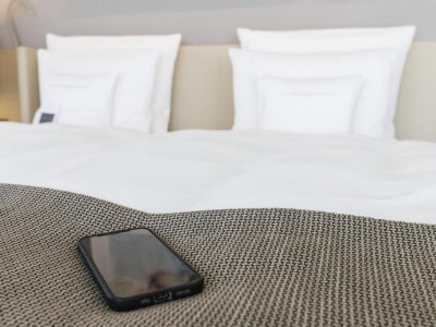 Ein Smartphone liegt am Fußende eines Betts in einem Hotelzimmer des "Öschberghof". (zu dpa: "Volldigital oder Funkloch: Hotels wollen technischen Komfort bieten") Foto: Philipp von Ditfurth/dpa