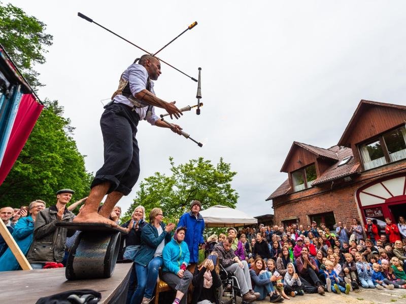 Ein Straßenkünstler vom "Chaos Variete" jongliert bei der Kulturellen Landpartie im Wendland auf einem Hof mit Fackeln.